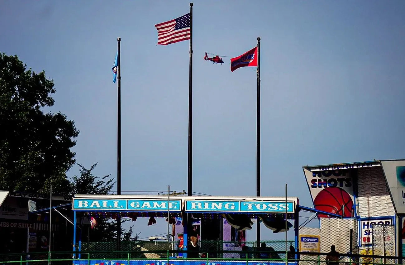 Flags flying above the ball game and ring toss stand on the ballpark concourse