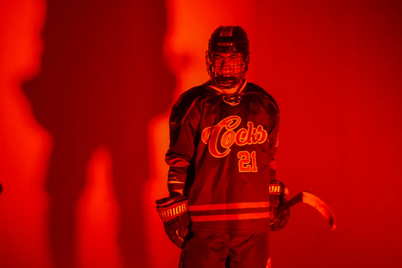 Gamecocks player number 21 breaking into a smile behind his cage under red light