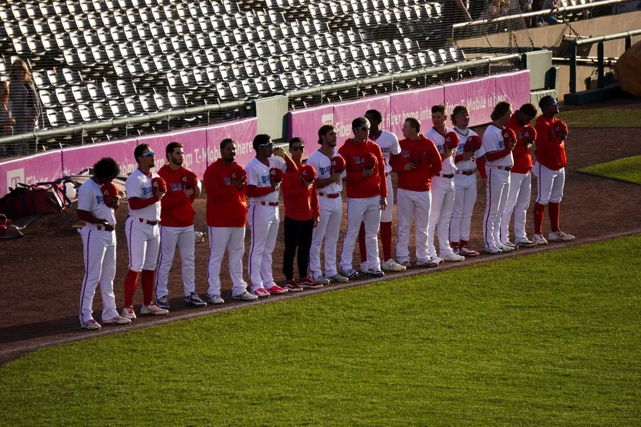 Team standing along the baseline with caps off for the national anthem