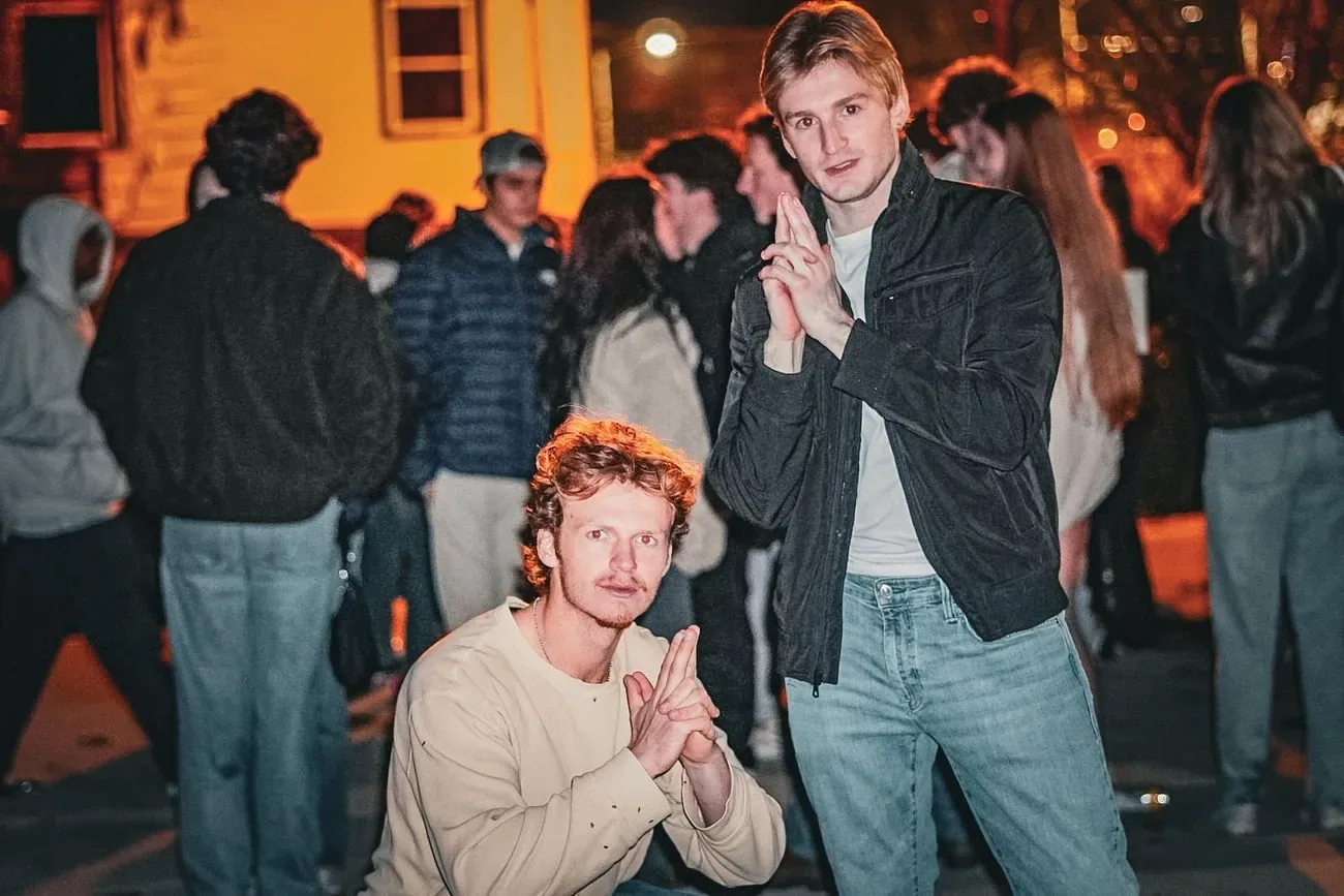 Two friends posing for the camera in a crowded backyard at night