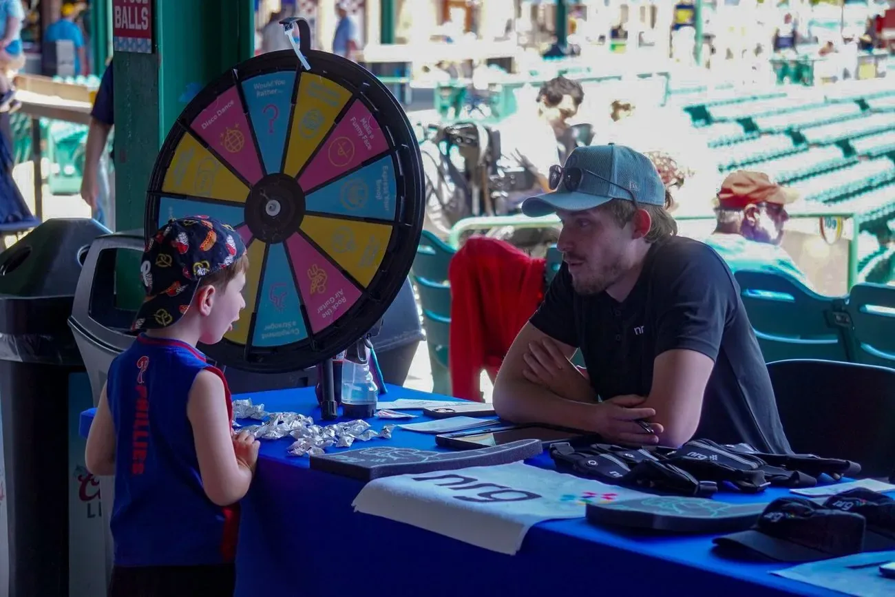 A boy spinning a sponsor prize wheel at a concourse activation table