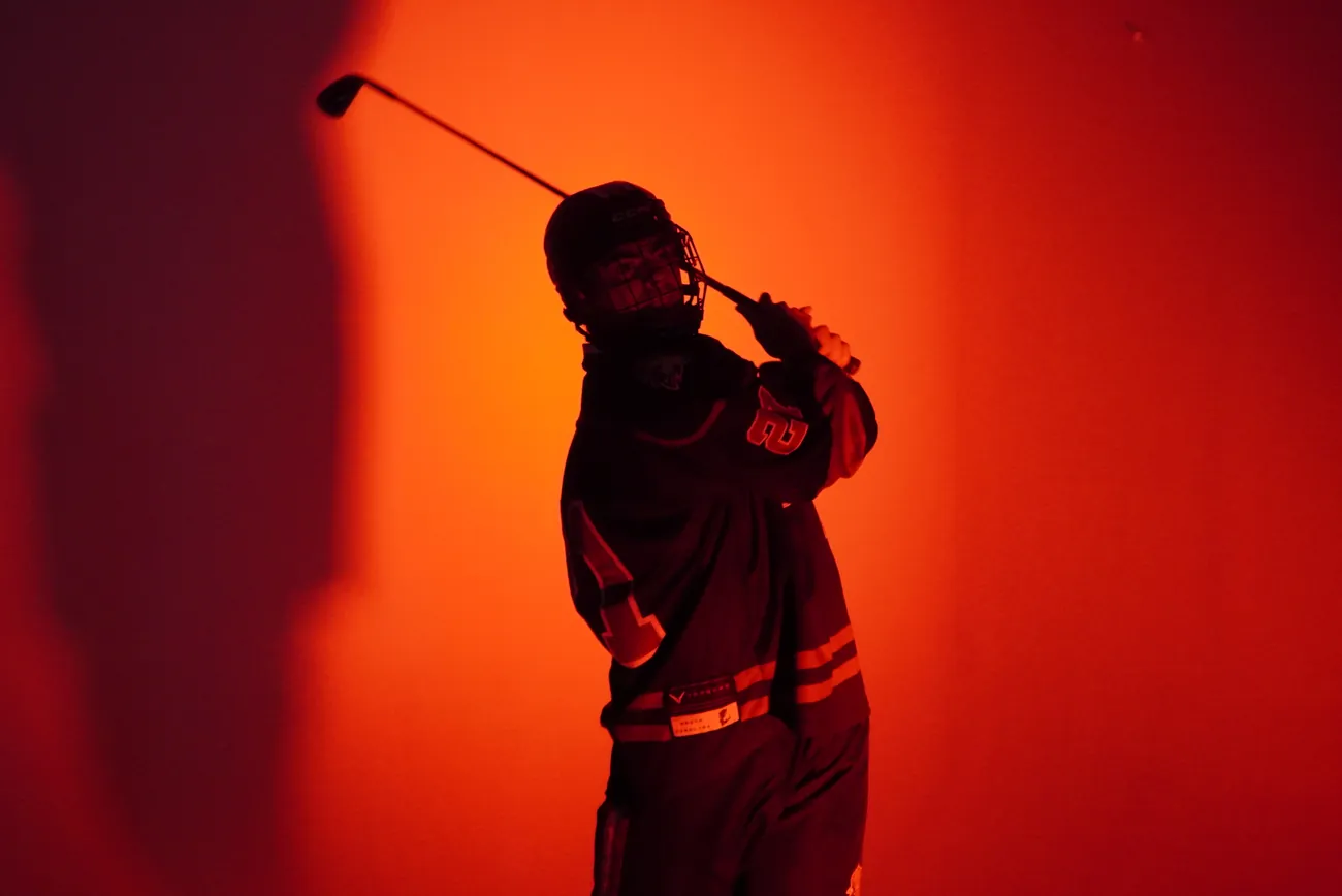 Gamecocks player swinging his hockey stick like a golf club, caught at the top of the follow through