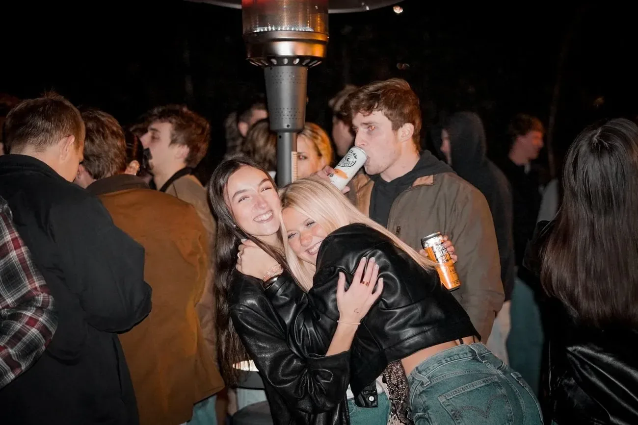 Friends laughing together under a patio heater at night