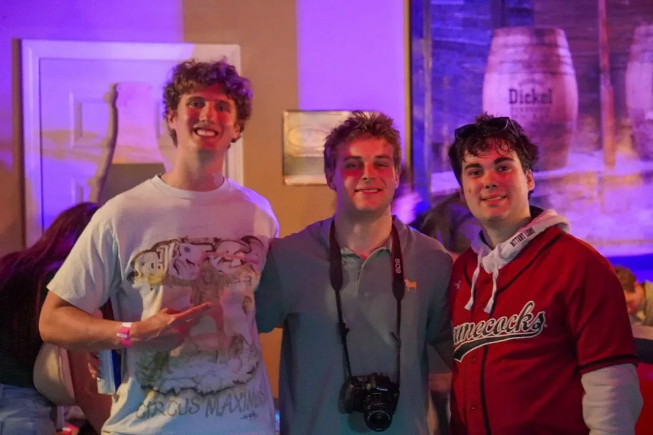 Three friends at a bar, one with a camera around his neck