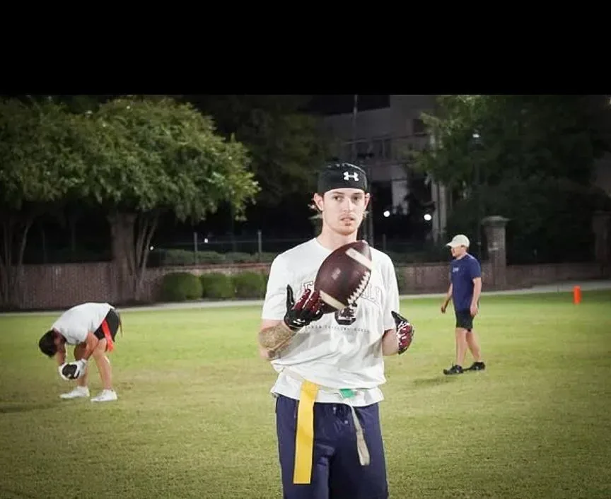 Flag football quarterback setting to throw under the field lights