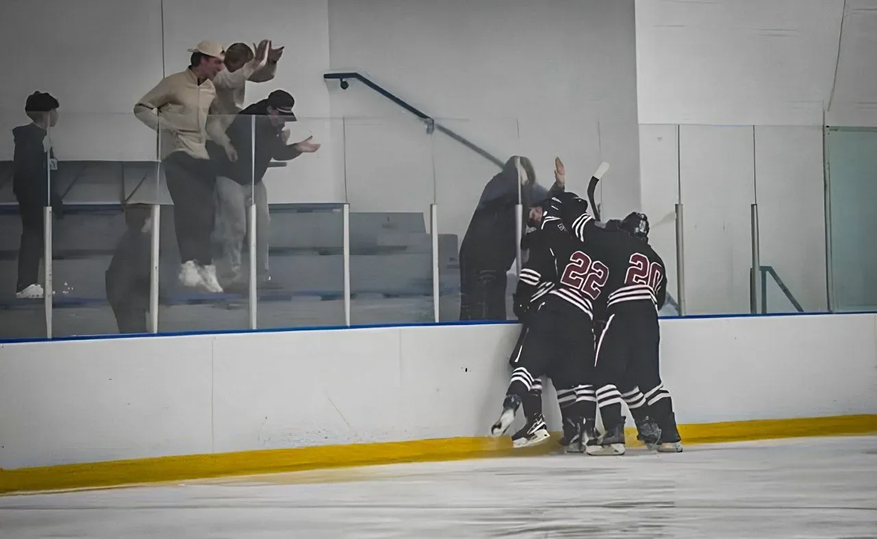 Carolina players piling into the corner boards to celebrate a goal