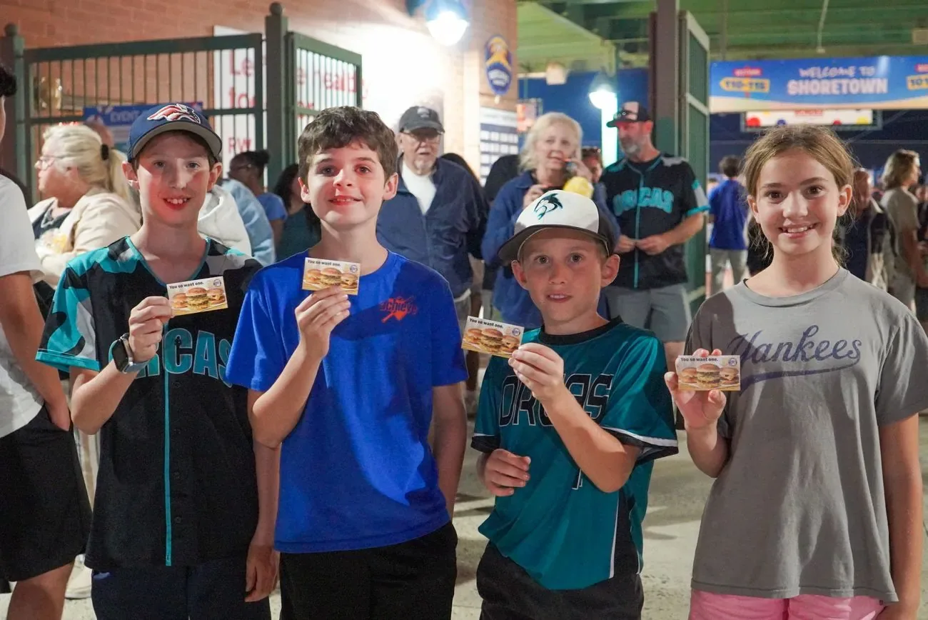 Four kids on the concourse holding up prize tickets they just won