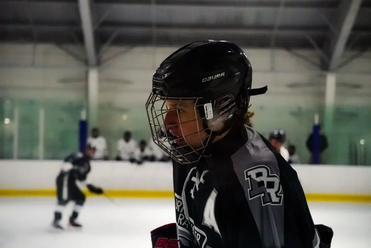 Bridgewater Raritan player in a cage helmet looking down the ice