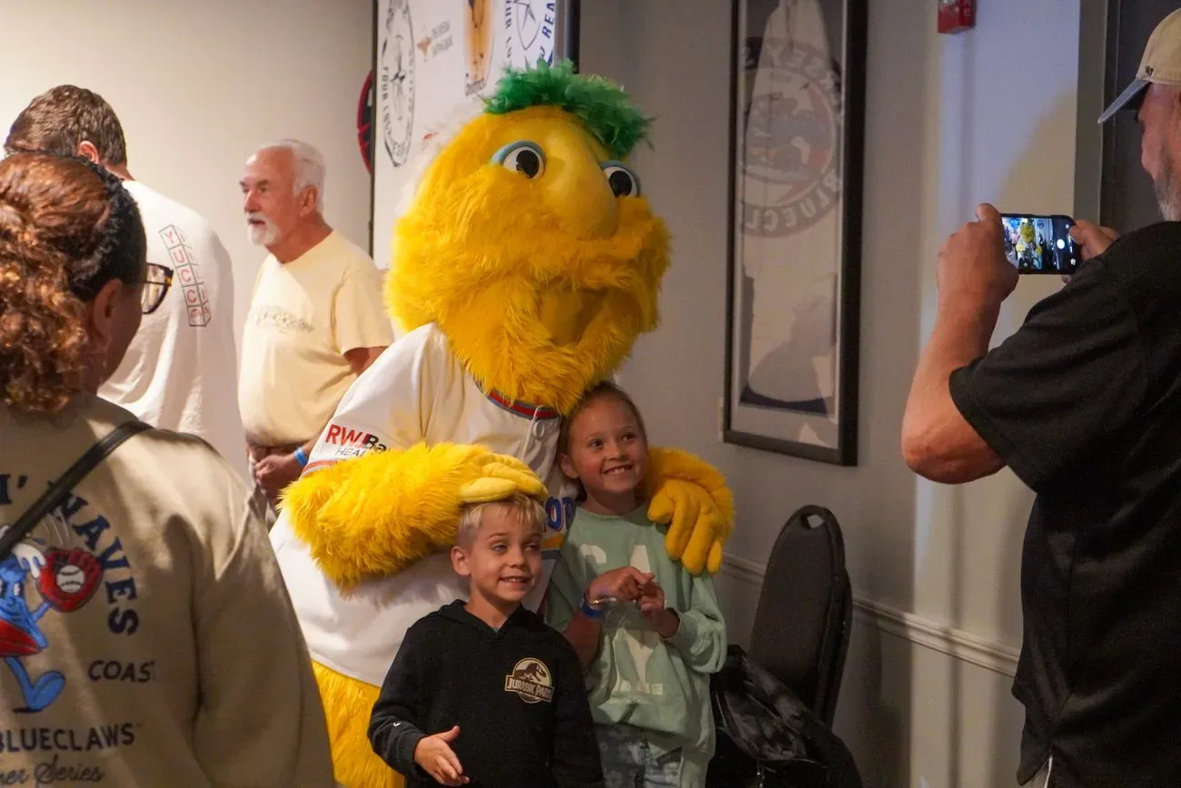 Buster posing with a family while a grandfather takes the photo on his phone