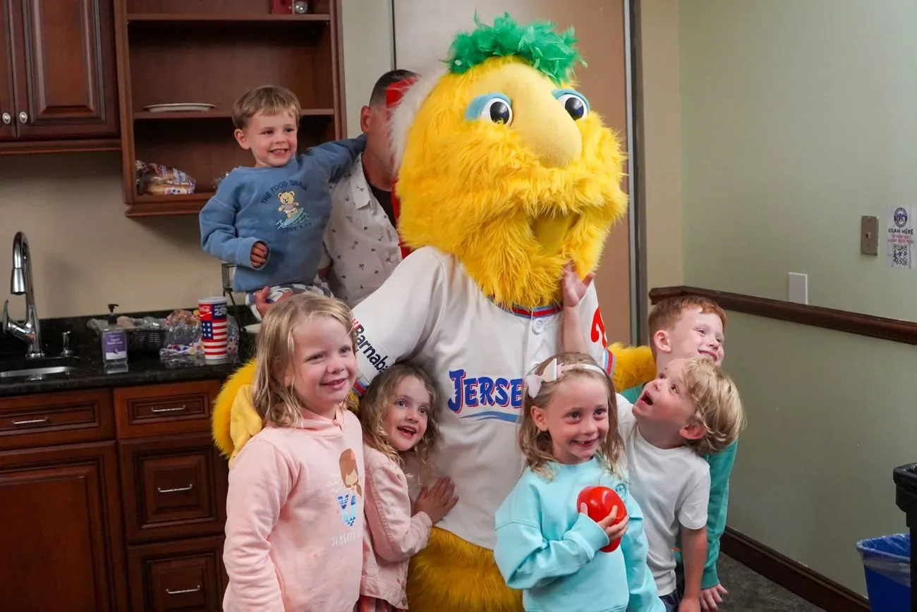 Buster surrounded by a group of kids in a ballpark suite