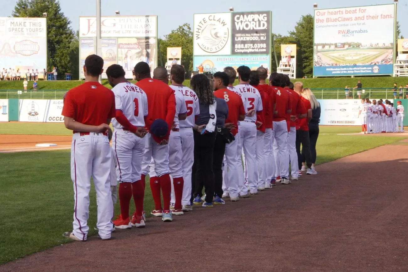 BlueClaws players lined up along the baseline with arms around each other before first pitch