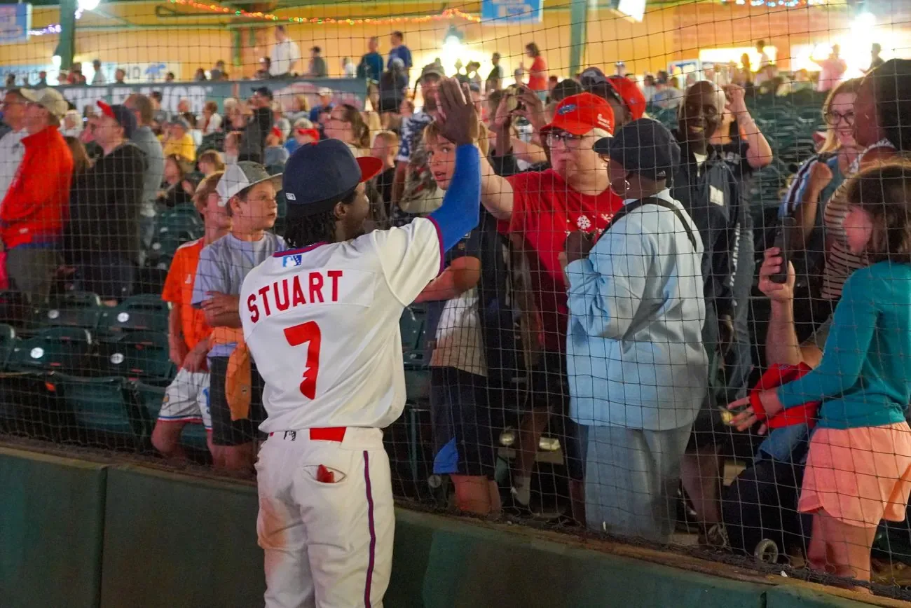 Player Stuart, number 7, high-fiving a line of fans through the netting after the game