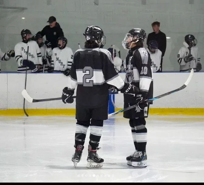 Two players talking in front of the bench between shifts