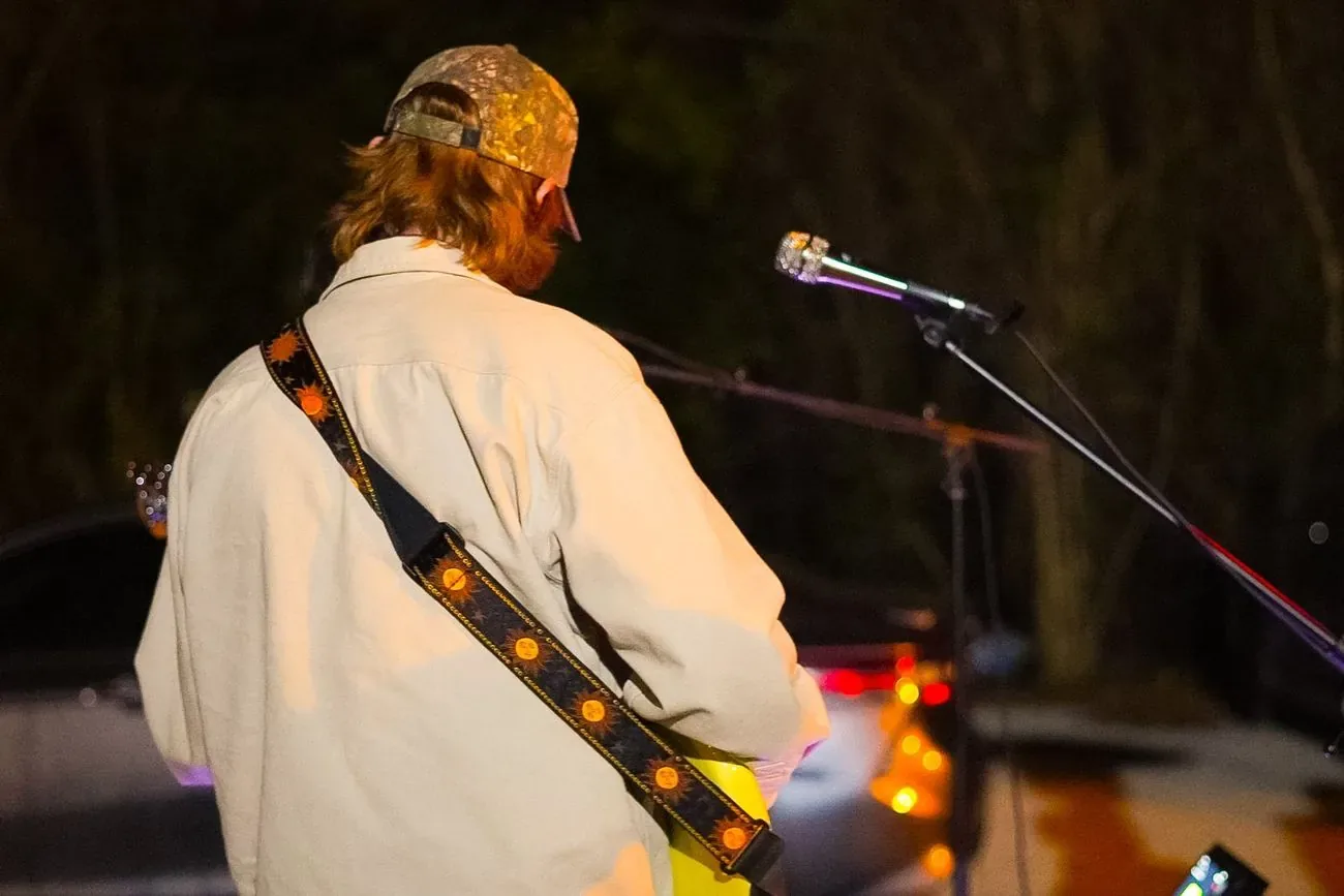 Singer seen from behind at the microphone on an outdoor stage at night