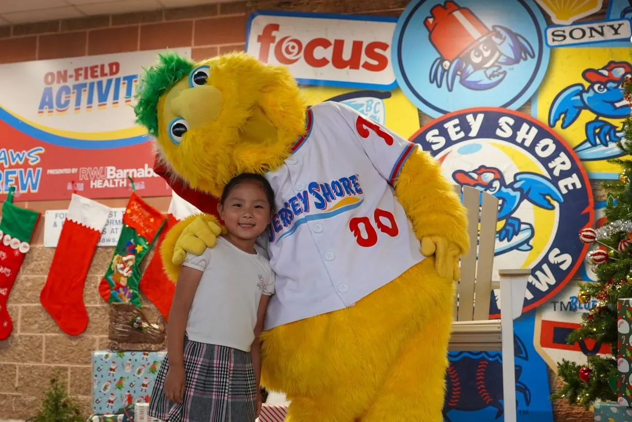 Buster posing with a young girl beside stockings and a decorated tree for Christmas in July