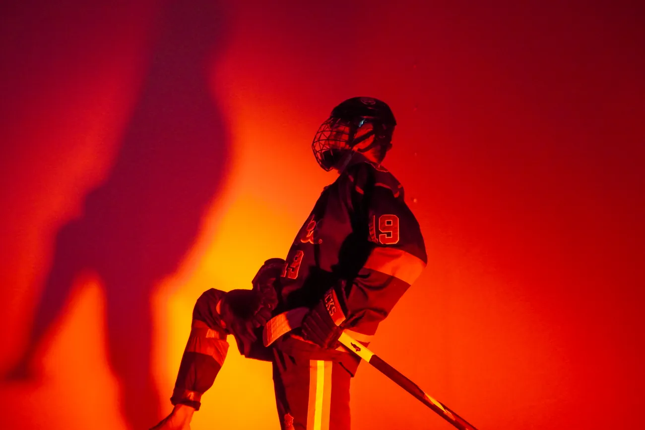 Gamecocks player number 19 in a power stance with one knee raised, lit red against the backdrop with his own shadow behind him