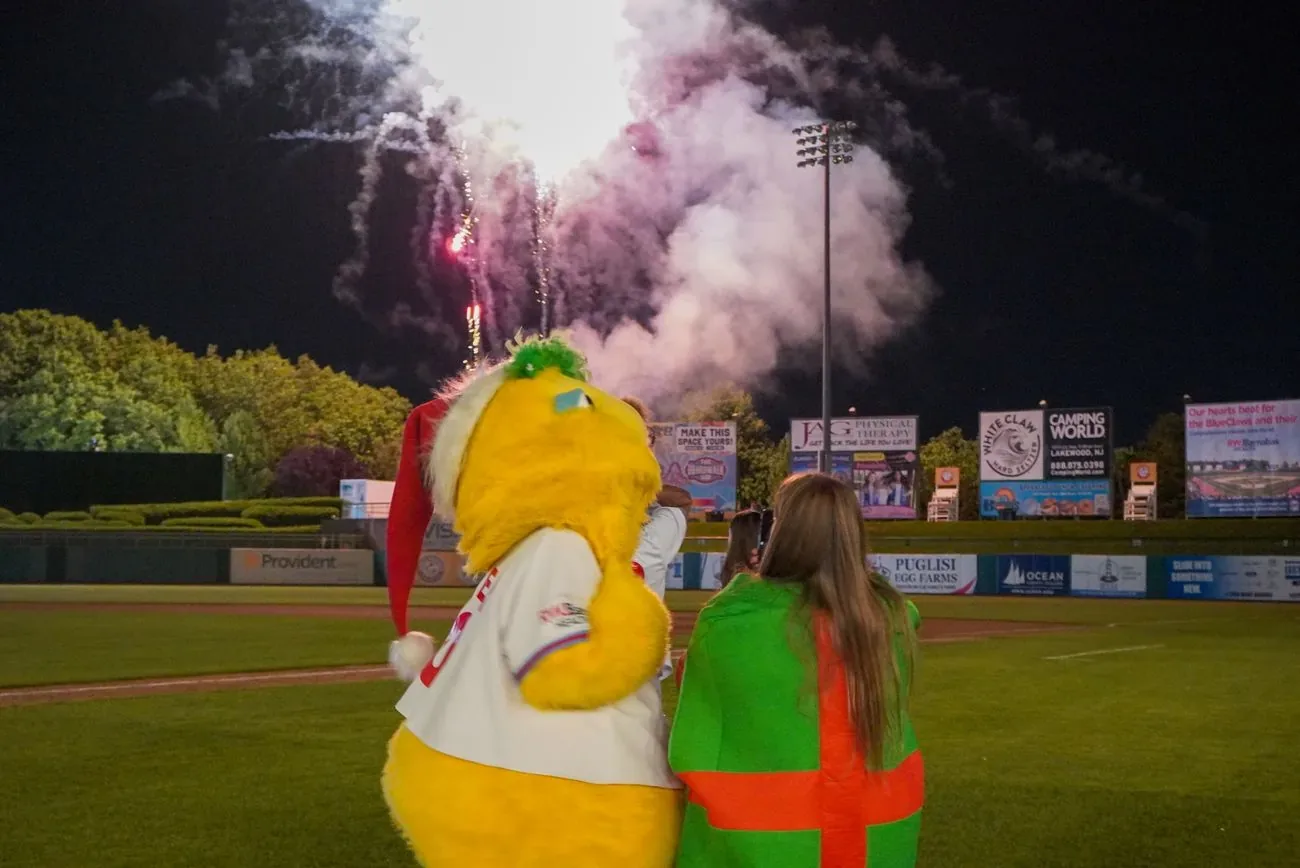 Buster and a fan watching fireworks burst over the outfield