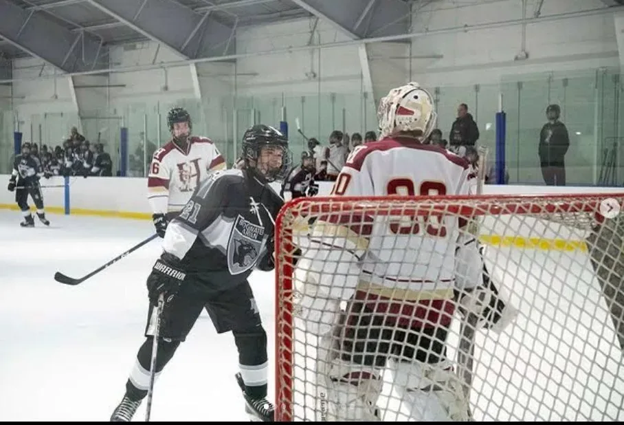 Goalie in white Gamecocks pads guarding the crease as an opposing player crashes the net