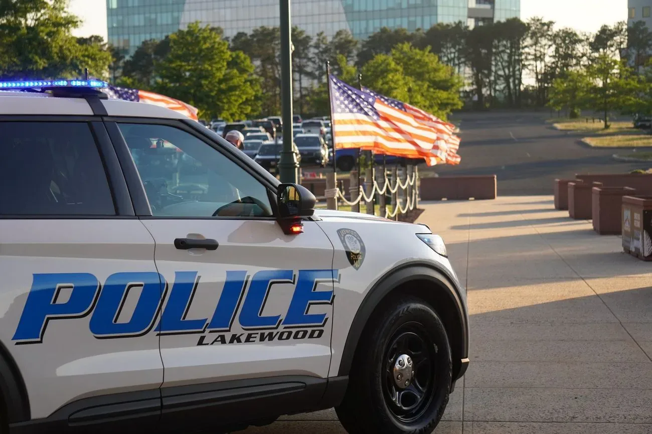 A Lakewood Police cruiser parked by the flagpoles outside the ballpark at sunset