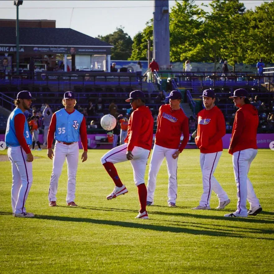 BlueClaws players in red warmup tops keeping a soccer ball up in the outfield before first pitch