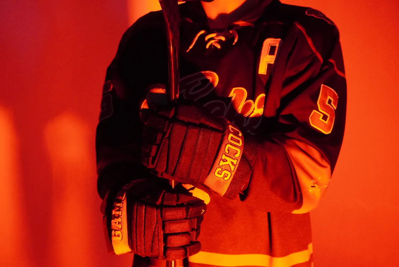 Close crop on a Gamecocks alternate captain's gloves gripping his stick, the letter A on his shoulder