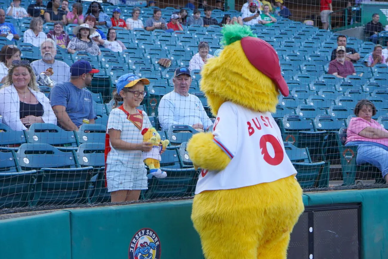 Buster the mascot working the seating bowl and handing something to a fan